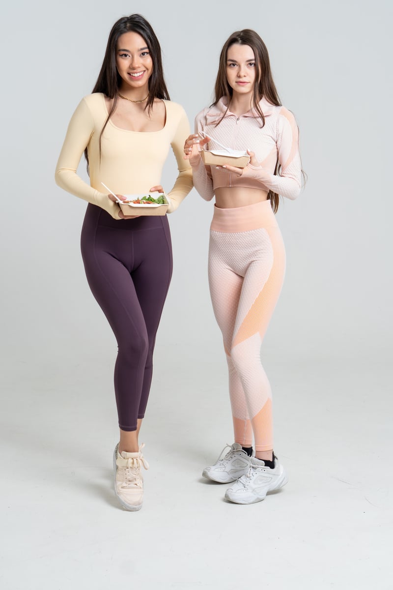 Two Young Women in Sports Clothing Eating Meal 