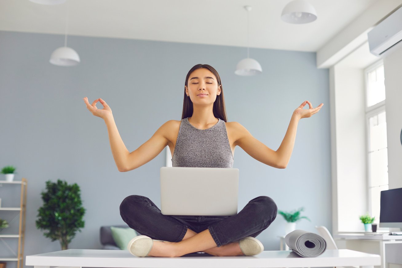 Office Worker with Positive Mindset Sitting on Desk in Easy Pose Meditating and Relaxing