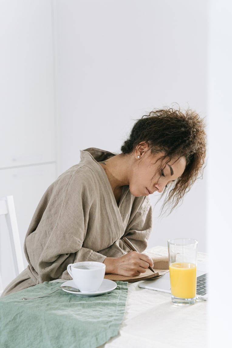 Woman in Brown Bathrobe writing on a Journal 